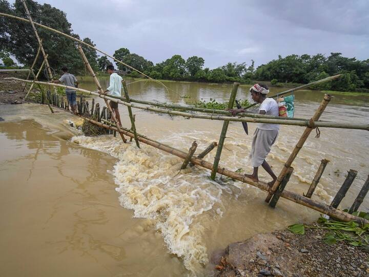 Villagers make a temporary bamboo bridge after a portion of a road was washed away due to flood following heavy rainfall at a village in Nagaon. The flood situation in Assam worsened on Wednesday following incessant rain. (Source: PTI)