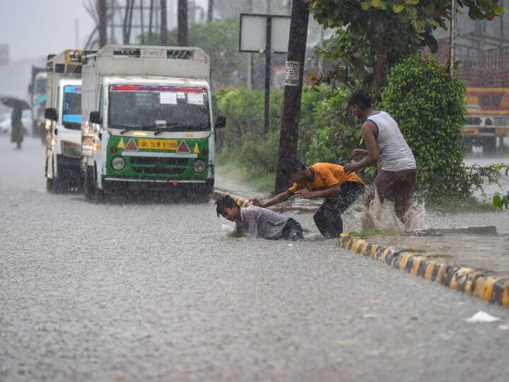 Boys play on a waterlogged road amid monsoon rains, in Ghaziabad. IMD also forecasts good amounts of rain for the next 10 days in the city and its adjoining areas after the onset. (PTI Photo)