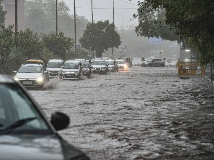 Vehicles ply on a waterlogged road amid monsoon rains, in New Delhi, Thursday. (PTI Photo)