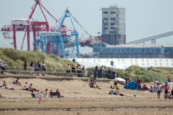 A heat haze shimmers over Crosby Beach as people relax in the warm weather on July 11, 2022 in Liverpool, United Kingdom. The Met Office warned of disruption to electricity, gas and water supplies, as well as cancellations and delays on trains and roads, with a danger to passengers and motorists stuck in stationary vehicles. Image Sources: Getty Images