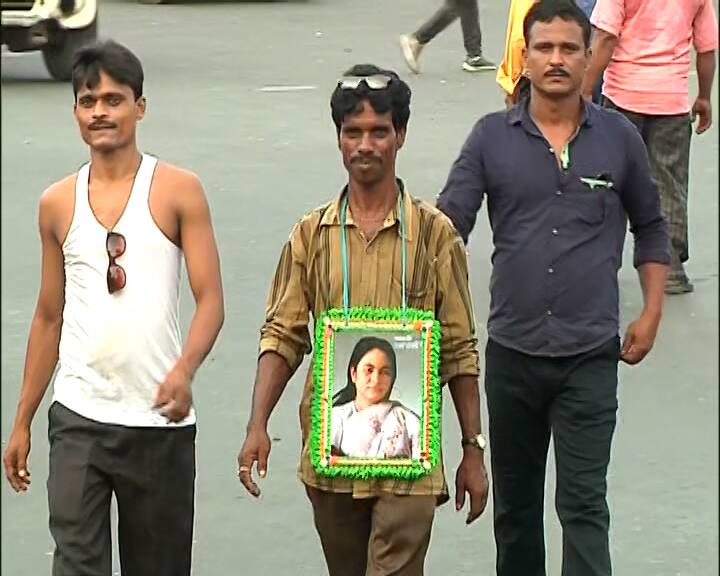 টুপিতে ঘাসফুল, বুকে মমতা বন্দ্যোপাধ্যায়ের ছবি দেওয়া প্ল্যাকার্ড ঝুলিয়ে একুশের সমাবেশে হাজির তৃণমূল কর্মী, সমর্থকরা।