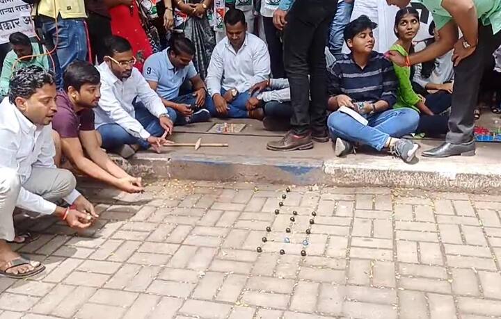 स्पर्धा परिक्षेचे विद्यार्थींनी रस्त्यावर गोट्या खेळत संताप व्यक्त केला.