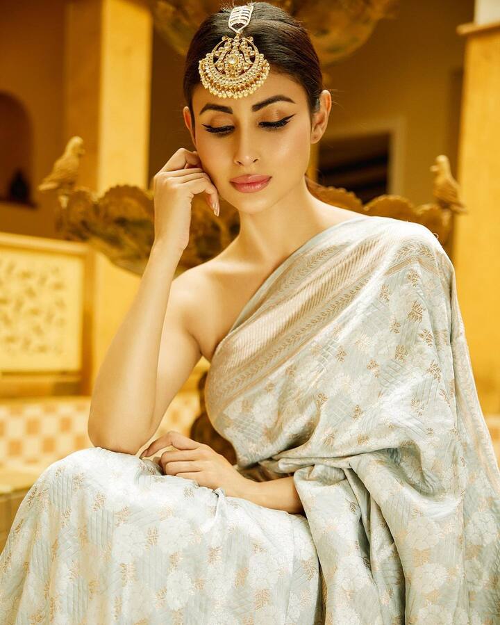 इन तस्वीरों में मौनी रॉय आइवरी कलर की साड़ी पहने नजर आ रही है. इसके साथ उन्होंने माथे पर बड़ा सा मांग टीका लगाया है.