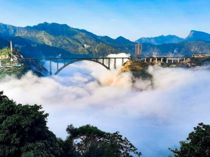 जम्मू कश्मीर में रियासी जिले के अंदर चिनाब नदी पर बना सबसे ऊंचा पुल किसी अजूबे से कम नहीं है. 18 साल की मेहनत के बाद यह प्रोजेक्ट अंतिम चरणों में है. श्रीनगर को देश से जोड़ने वाला यह पुल कई मायनों में कई खासियतें रखता है. नीचे बादल और ऊपर पुल देखकर आप घर बैठे-बैठे ही रोमांचित हो उठेंगे.