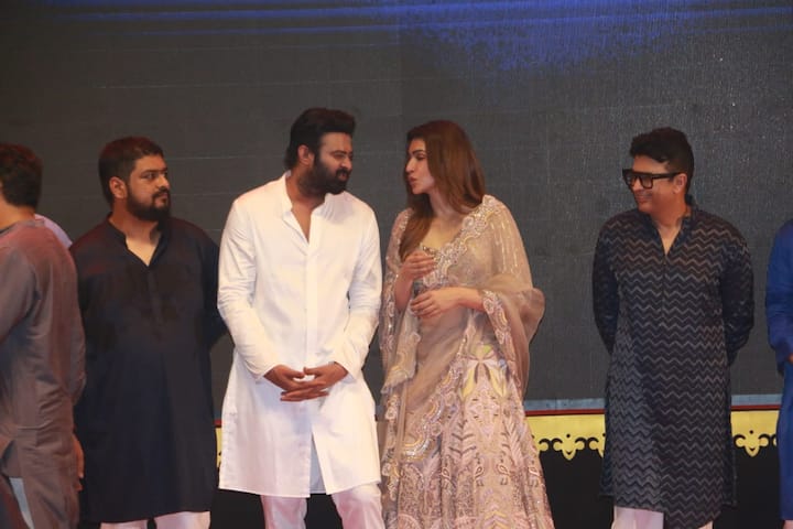 হালকা পিচরঙা ঝলমলে লেহঙ্গা, খোলা চুল, 'আদিপুরুষ'-এর টিজার লঞ্চ অনুষ্ঠানে ঝলমল করছিলেন অভিনেত্রী কৃতি শ্যানন। আর তাঁর পাশেই সাদা লম্বা কুর্তায় প্রভাস। ছবির নায়ক।