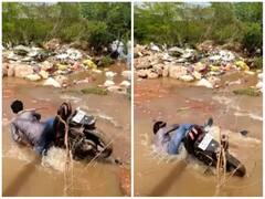 पानी से भरे सड़क पर बने गड्ढे में जा समाया बाइक सवार, होश उड़ा देगा वीडियो