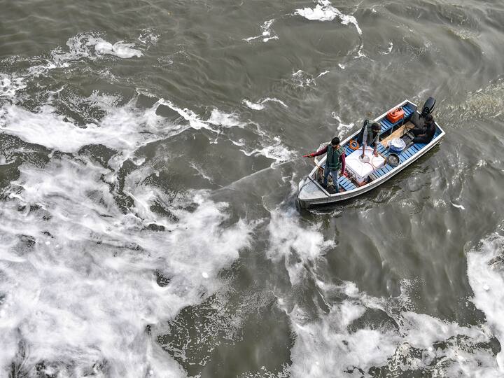 A Delhi Jal Board official sprays chemical to dissolve toxic foam floating in the polluted waters of Yamuna river, ahead of 'Chhath Puja' celebrations at Kalindi Kunj in New Delhi, Friday, Oct. 28, 2022. (PTI Photo)