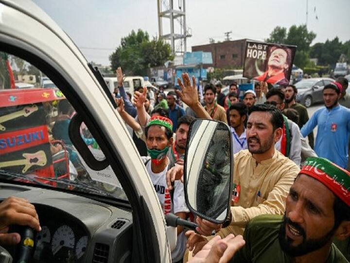 Supporters of former Pakistani prime minister Imran Khan, stop vehicles as they block a road during a protest near the container truck. (Image Source: AFP)