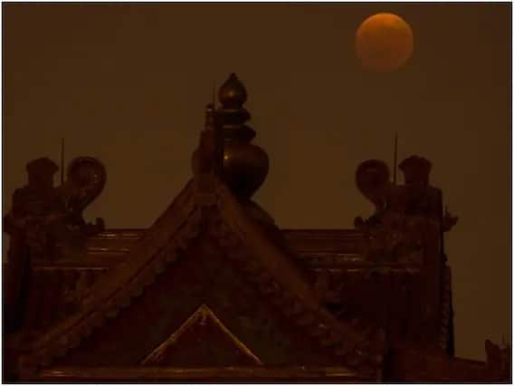 ચંદ્રની સપાટી પર પહોંચતો પ્રકાશ સૌપ્રથમ પૃથ્વીના વાતાવરણમાંથી પસાર થાય છે, જેના કારણે ચંદ્ર લાલ રંગનો બને છે. આ તસવીર ચીનના બેઈજિંગની છે. (એપી ફોટો/માર્ક સ્કીફેલબીન)