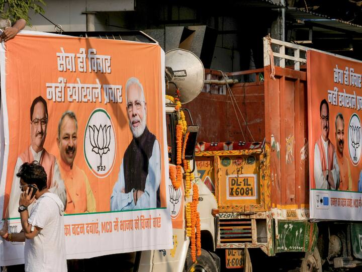Workers attach a banner of BJP to a truck as part of party's campaign for the upcoming Municipal Corporation of Delhi (MCD) election, outside BJP office in New Delhi, Sunday, Nov. 20, 2022. (Image Source: PTI)