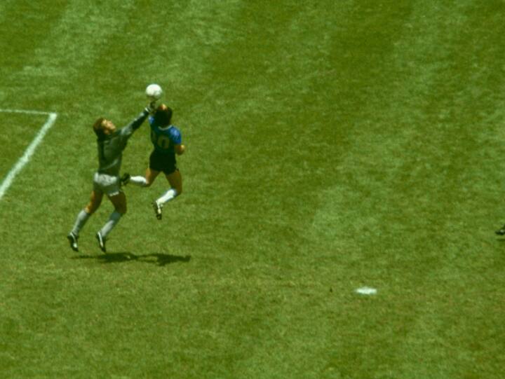 Argentina player Diego Maradona outjumps England goalkeeper Peter Shilton to score with his 'Hand of God' goal as England defenders Kenny Sansom (top) Gary Stevens (c) and Terry Fenwick look on during the 1986 FIFA World Cup Quarter Final at the Azteca Stadium on June 22, 1986 in Mexico City, Mexico. (Image Source: Getty Images)