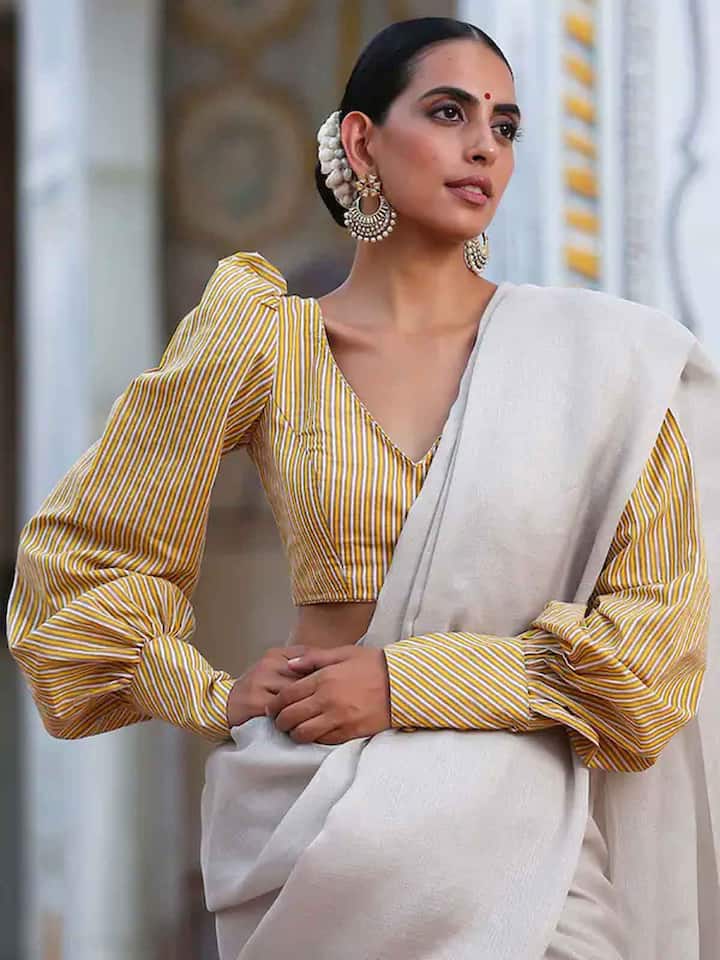 पीजेंट स्लीव ब्लाउज का डिजाइन बिल्कुल ट्रेंड में बना हुआ है.इस तरह किस लिए थोड़ी सी पफी होती है. इसमें पूरा हाथ कवर हो जाता है. पीजेंट स्लीव्स ज्यादातर वी नेक ब्लाउज पर ही बनाया जाता है. अगर आप अपनी सिंपल साड़ी को एलिगेंट लुक देना चाहती हैं, तो इस तरह की ब्लाउज डिजाइन करवा सकती हैं..