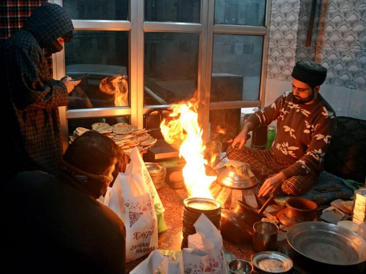 A chef pours hot oil on plates as he serves 'Harissa' to waiting customers on a cold winter morning, at a shop in Srinagar, on Thursday. With no forecast of fresh snowfall, the cold wave conditions will intensify further. (Source: PTI)