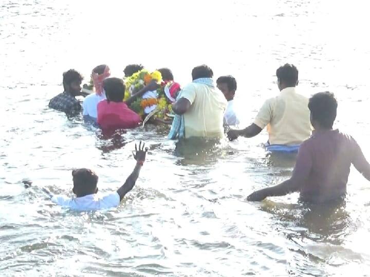 இறந்தவர் உடலை அடக்கம் செய்வதற்கு கழுத்தளவு நீரில் ஆபத்தான முறையில் பயணம் செய்யும் ஊர்மக்கள்