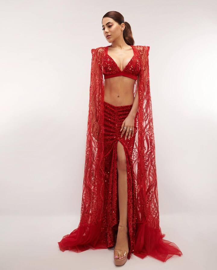शिमरी एक बार फिर से ट्रेंड में आ गया है. निक्की ने भी रेड कलर की शिमरी ड्रेस पहनी हैं. उन्होंने यहां थाई हाई स्लिट स्किन फिट स्कर्ट और बेहद डीपनेक ब्लाउज कैरी किया है. इसके साथ उन्होंने मैचिंग का श्रग भी पहना है. आप भी पार्टी के लिए इस तरह तैयार हो सकती हैं.