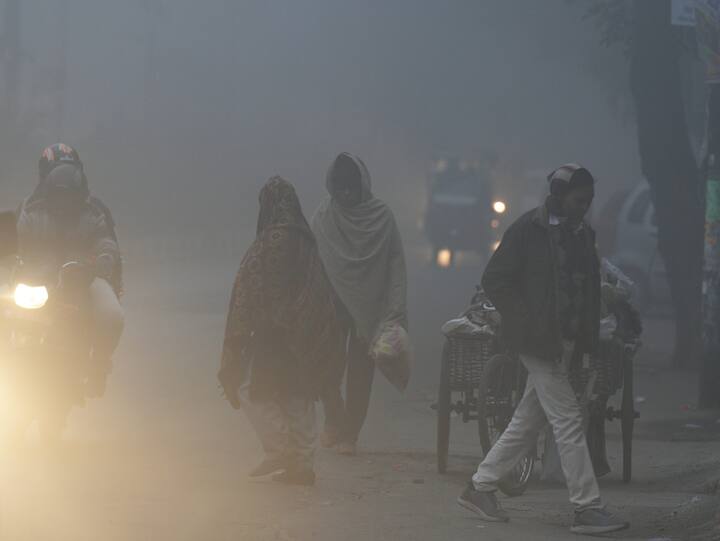 Commuters on a road amid low visibility due to a thick layer of fog on a cold winter morning, in New Delhi.