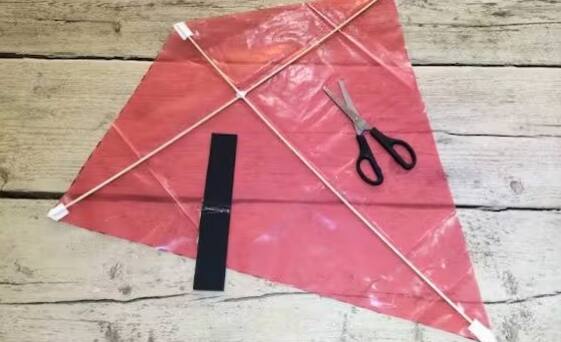 T ਸ਼ੇਪ ਬਣਾਉਣ ਲਈ ਪਤੰਗ ਦੇ ਸੈਂਟਰ ਵਿੱਚ ਡੋਵੇਲ ਰੱਖੋ। ਪਤੰਗ ਦੀ ਲੰਬਾਈ ਨਾਲ ਮਿਲਾਉਣ ਦੇ ਲਈ ਇੱਕ ਐਕਸਟ੍ਰਾ ਕਿਨਾਰਿਆਂ ਨੂੰ ਕੱਟੋ ਅਤੇ ਇਸ ਨੂੰ ਚੰਗੀ ਤਰ੍ਹਾਂ ਟੇਪ ਕਰੋ।