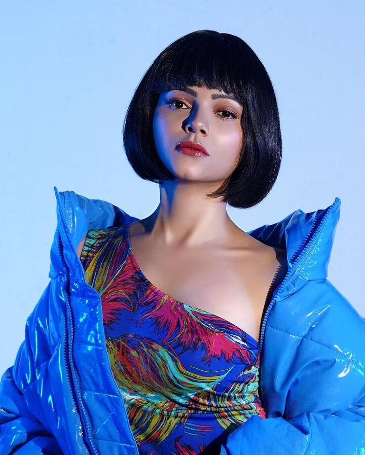 रुबीना इन तस्वीरों में ब्लू कलर की वन शोल्डर ड्रेस में नजर आ रही हैं और इस ड्रेस का प्रिंट फ्लोरल है. उन्होंने अपनी ड्रेस के साथ ब्लू पफर जैकेट पहनी है जो कि काफी ढीली-ढाली लग रही है.