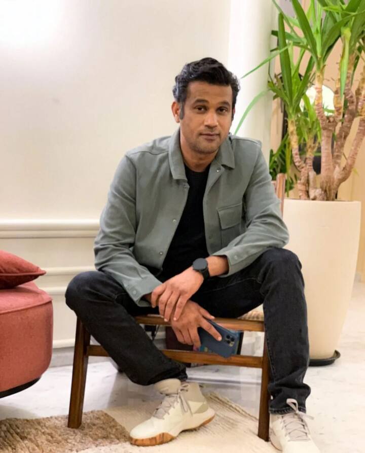 Sohum Shah is wearing an open button-checkered shirt with a plain black T-shirt inside.