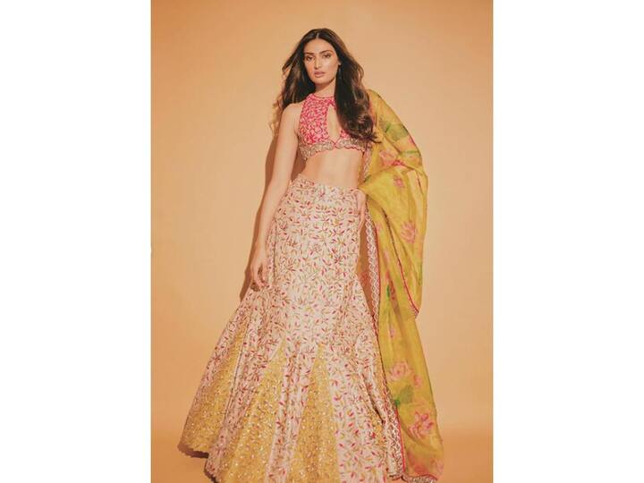 अथिया शेट्टी का ये लहंगा लुक काफी डिफरेंट है, ट्रेडिशनल एंब्रॉयडरी वाले फिश कट लहंगे के साथ पिंक ब्लाउज में पॉप कलर ऐड किया गया है जो काफी सेक्सी टच दे रहा है.