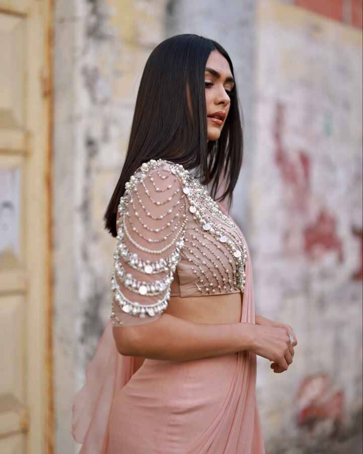 मृणाल इस पिंक कलर की रेडी टू वियर साड़ी में बहुत ही ग्रेसफुल लग रही हैं, साड़ी को डिजाइनर रिधि मेहरा के कलेक्शन से लिया गया है,साड़ी की सारी खूबसूरती इसके ब्लाउज से बनी हुई है. सिल्वर जरी की एंब्रॉयडरी वाली लॉन्ग स्लीव ब्लाउज साड़ी की खूबसूरती में चार चांद लगा रहा है.