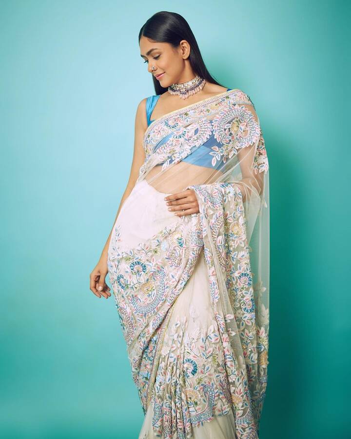 मृणाल की वाइट कलर की हैवी एंब्रॉयडरी वाली साड़ी भी बहुत ही खूबसूरत है, इस पर फिरोजा रंग के भी वर्क किए गए हैं जो इसे कंट्रास्ट देकर बहुत ही दमदार लुक दे रहा है. मृणाल ने इसे बहुत ही खूबसूरती से कैरी किया है.इसके साथ मृणाल ने फिरोजा रंग की स्ट्रैपी ब्लाउज कैरी किया है.