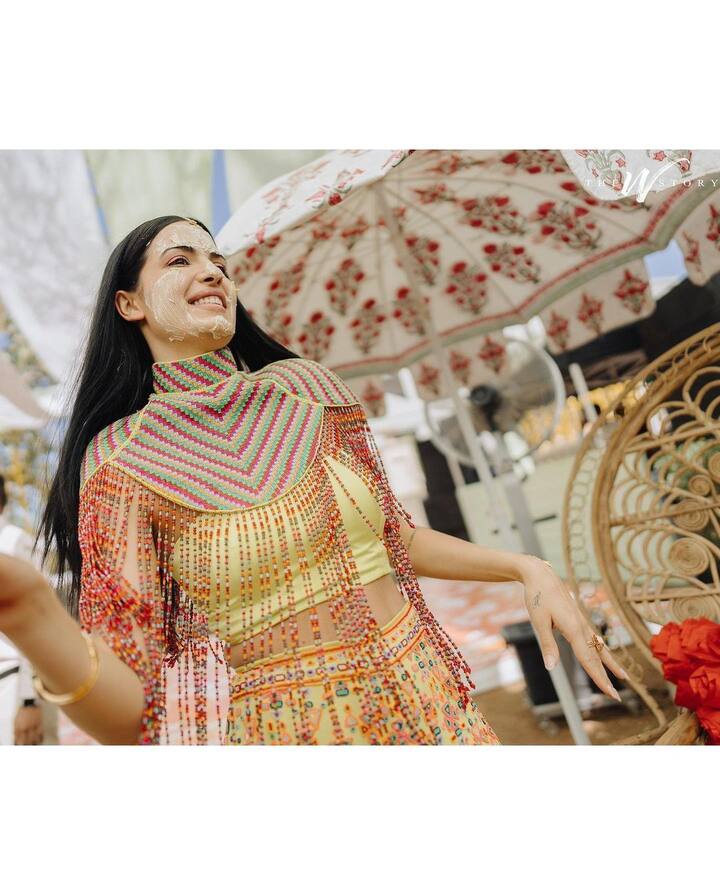 At the mehendi and haldi ceremony, Natasa donned a traditional yellow ethnic outfit with with a multicoloured tasselled beaded cloak. She accessorised with just a tiny maang teeka.