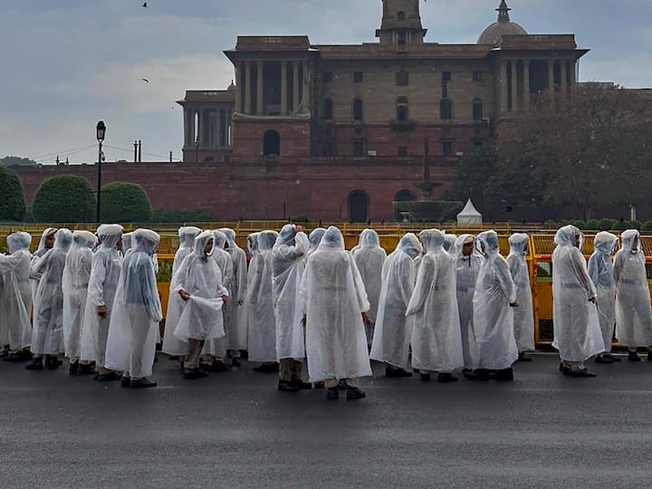 Security personnel at Vijay Chowk wear raincoats to shield themselves from rain in New Delhi on Friday.