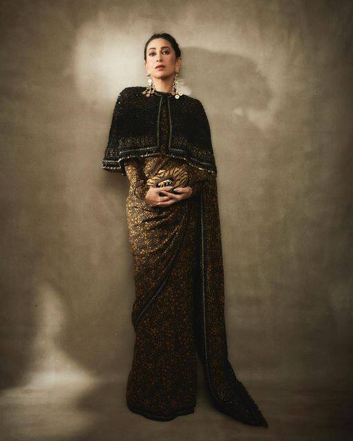 Karisma Kapoor looked beautiful in a very vintage sense. She wore a black printed saree with a long tail shrug
