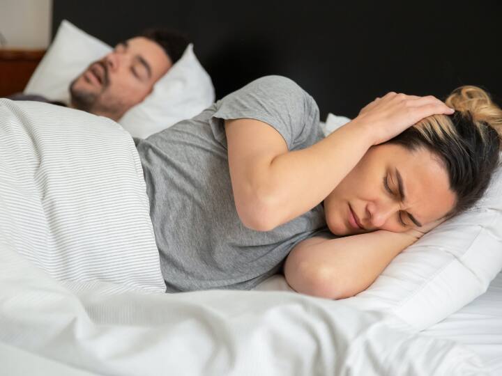 Snoring Tips: अनियमित लाइफस्टाइल के चलते सोते समय खर्राटे लेना एक आम बात है. लेकिन ये एक गंभीर स्वास्थ्य समस्या का संकेत भी हो सकता है.