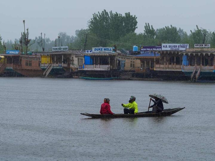 A boatman is seen rowing his boat in Dal Lake with tourists on it. The tourists enjoyed the weather as the temperature came down. The minimum temperature dropped to 10 degrees. (Image: PTI)