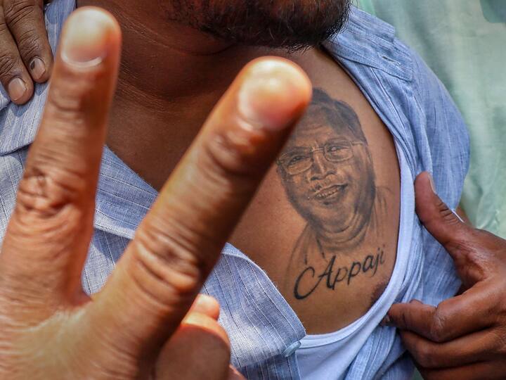 A supporter of Congress leader Siddaramaiah celebrates near his residence in Bengaluru. Flashes victory sign while showing a tattoo of Karnataka CM-designate.