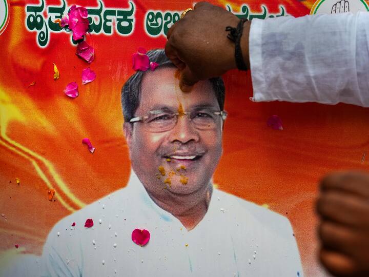A poster of senior Congress leader Siddaramaiah being applied 'tilak' as his supporters celebrate outside his residence, in Bengaluru.