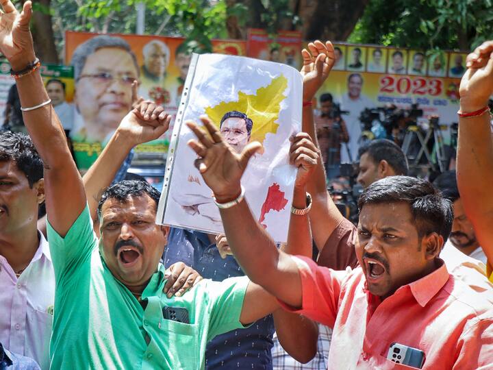 People hold posters with an image of Siddaramaiah's over the map of Karnataka, dance and celebrate outside the leader's residence.