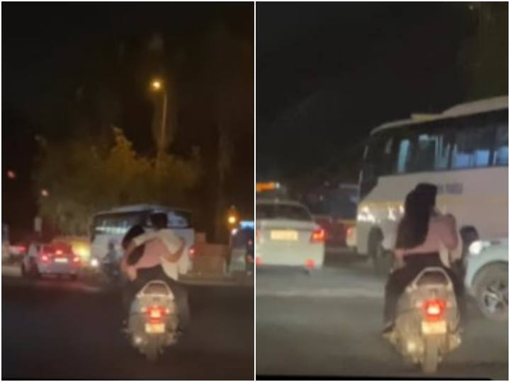 A couple is seen romancing while riding a scooty on road video goes viral Video: अजीबोगरीब ढंग से स्कूटी पर बैठे कपल का वीडियो हुआ वायरल, लोग बोले- 'प्यार में कम ना रहे'