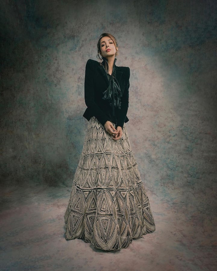 She wore a black ruffled blouse with a frilly bow on the front and lace embroidery at the neck with a peplum-style blazer that has padded shoulders and full-length sleeves. (Image Source: Instagram/Maneka Harisinghani)