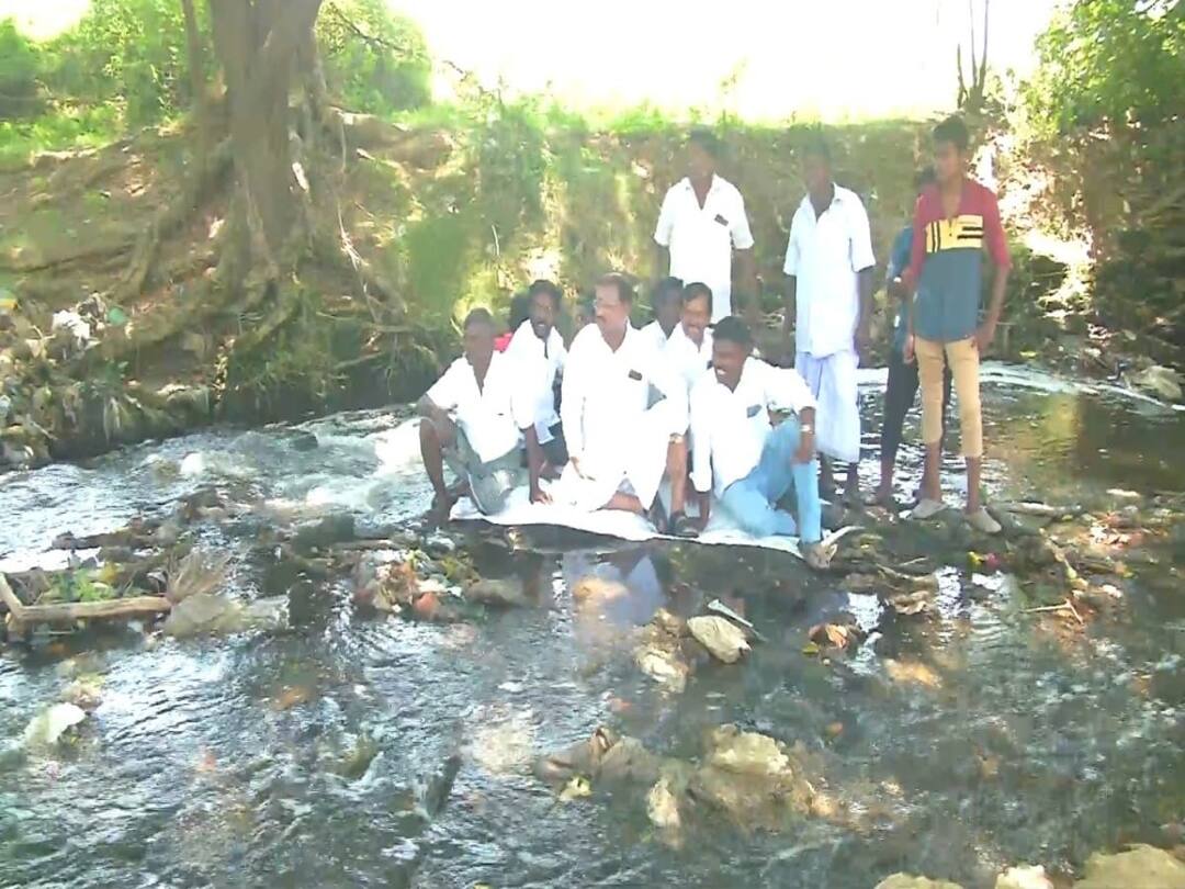 தாமிரபரணியில் கழிவு நீர் கலப்பு -  கழிவுநீர் மீது பேனரை விரித்து உட்காந்து காங்கிரஸ் நூதன போராட்டம்