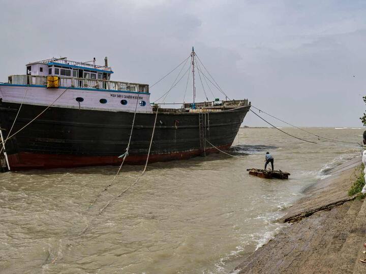 A worker fixes a cargo ship with ropes at the seashore as part of precautionary measures ahead of cyclone Biparjoy making landfall at Mandvi in the Kutch district on Thursday. (Source: PTI)