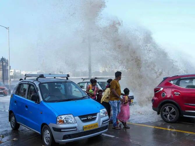 பொதுமக்கள் சாலையை கடக்கும் போது பிபர்ஜாய் புயலின் அலை உயரமாக அடிக்கும் போது எடுத்த புகைப்படம். (Source: PTI)