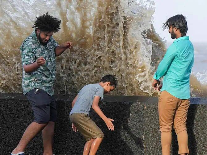 இளைஞர்கள் சிலர் அலையில் இருந்து தப்பிக்க முயல்கின்றார்கள். (Source: PTI)