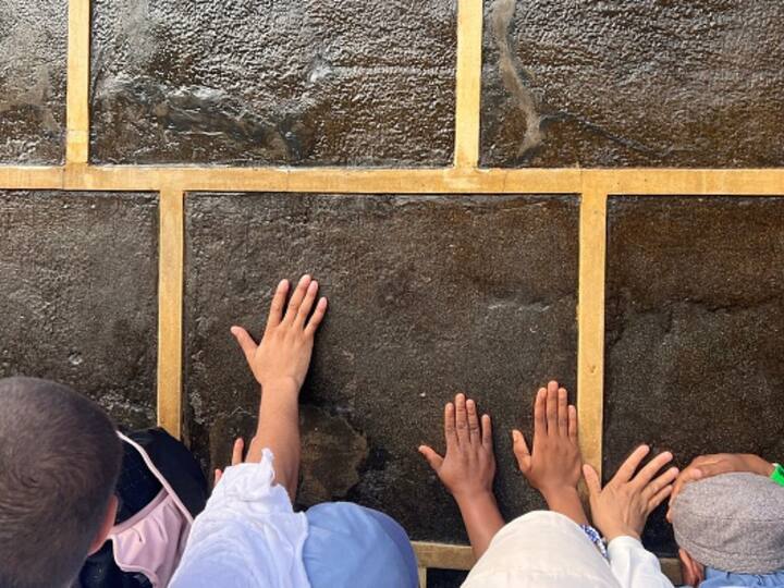 Muslim worshippers touch the Kaaba, Islam's holiest shrine, at the Grand Mosque in the holy city of Mecca. Image Source: Getty Images