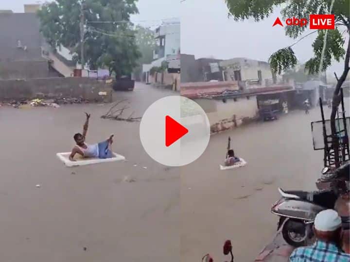 Gujarat heavy rainfall man enjoying flood water by lying on thermocol viral video थर्मोकोल पर लेटकर बाढ़ के पानी का मजा ले रहा शख्स, Video देखकर नहीं रोक पाएंगे हंसी