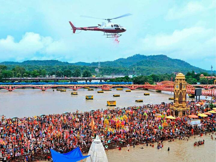 A helicopter was seen showering flowers on Kanwariyas (Lord Shiva devotees) gathered at Har Ki Pauri Ghat to collect holy water from the Ganga river during 'Kanwar Yatra' in the holy month of ‘Shravan’ in Haridwar on Thursday. (Source: PTI)