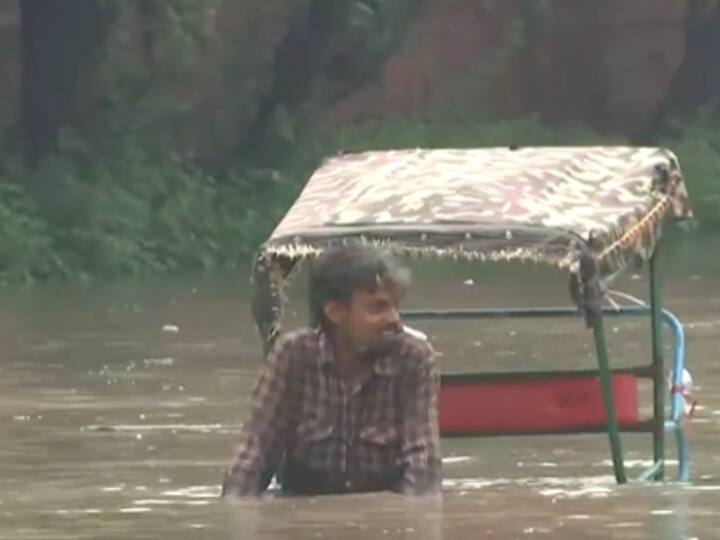 A rickshaw-puller pedals through chest-deep water in the flooded area near Red Fort of Delhi. (Image Source: Twitter/@ANI)