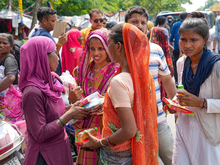 People wait in queue to receive the provisions distributed by Delhi Health Minister Saurabh Bharadwaj at a flood-relief camp. (Image Source: PTI)