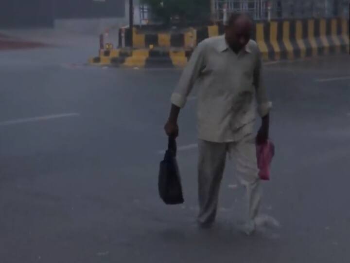 A man wades through a waterlogged road in Noida's Sector 20 early Wednesday morning during heavy rainfall. (Source: ANI)