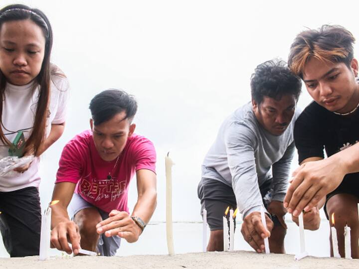 Residents offer prayers and candles for those killed in the boat capsise incident in the Philippines. (Source: Getty)