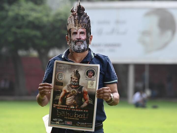 Man wearing a Rahul Gandhi mask holds a Bahubali poster with Rahul Gandhi's face on it at the AICC headquarters in Delhi on Friday. (Source: Getty)