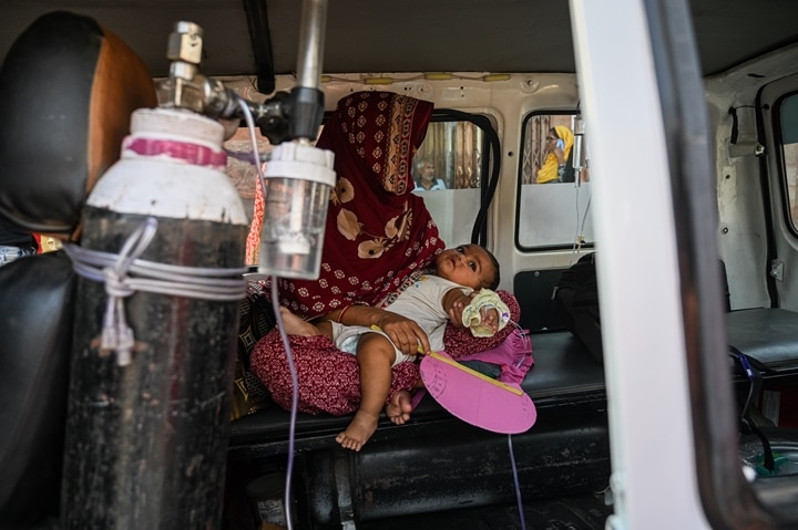 A woman sits inside an ambulance with her child, who is suffering from respiratory problems, at a hospital in Kolkata (Getty)