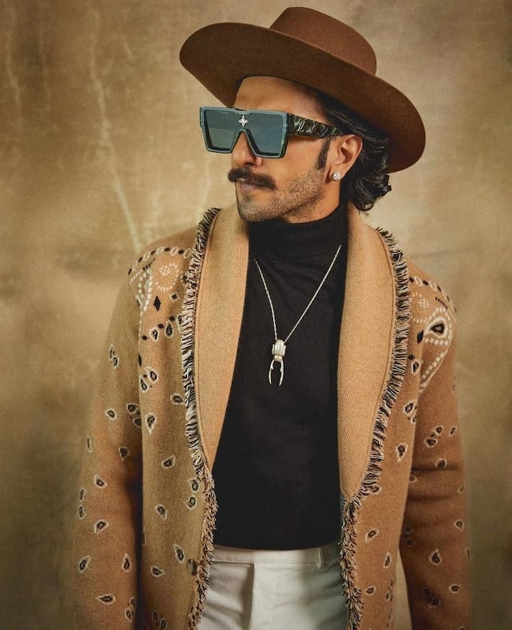 Cowboy swag: Bringing up the cool cowboy vibes to the forefront, Ranveer donned a long brown jacket blending it perfectly with a hat. This is what he is good at, 'Nailing an old fashion style in the modern era'.